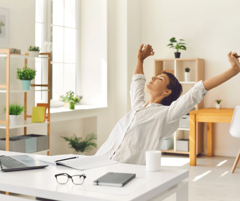 A person taking a break and stretching at their desk as a way to maintain boundaries over time