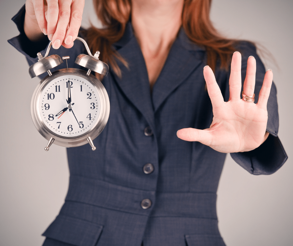 A hand holding up a clock as a symbol for setting boundaries