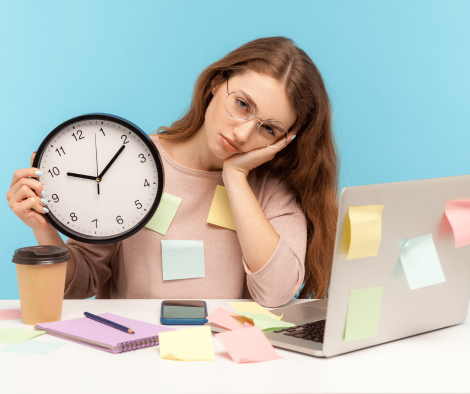 person sitting at a desk, perhaps looking stressed or overwhelmed, with a clock in the background indicating a late hour.